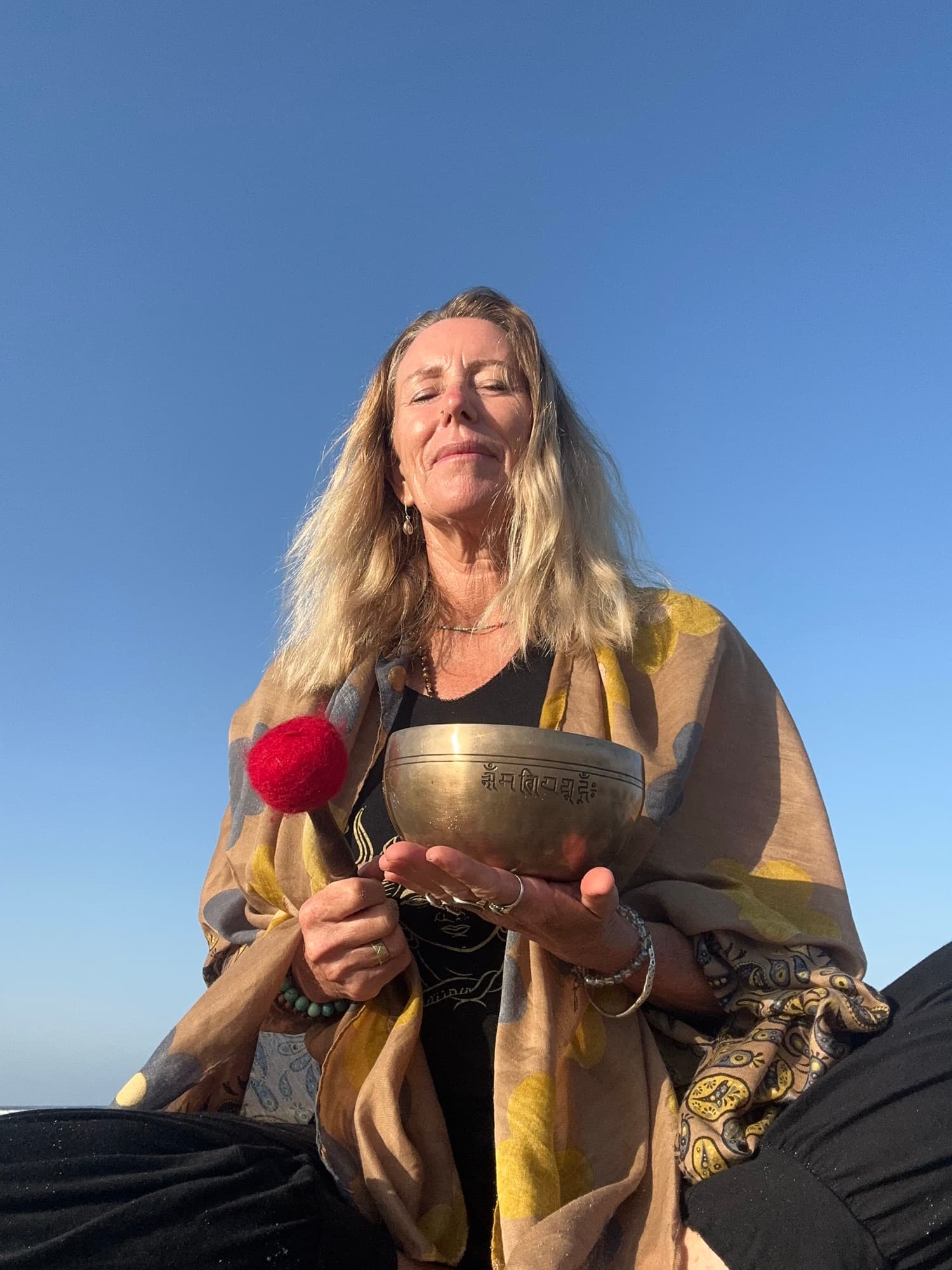 Justine holding a Tibetan singing bowl against an open sky